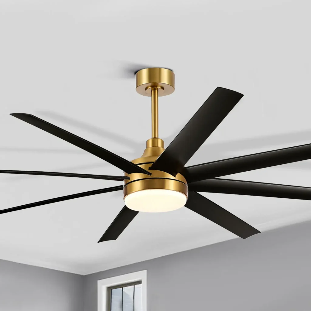 Modern ceiling fan with a gold base and black blades, featuring an integrated light fixture, mounted on a white ceiling.